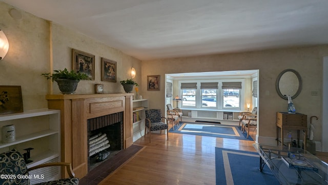 living area featuring a fireplace with flush hearth and wood finished floors