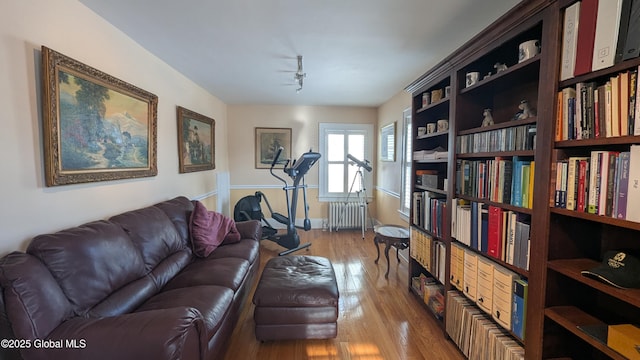 living area featuring track lighting, radiator heating unit, and wood finished floors