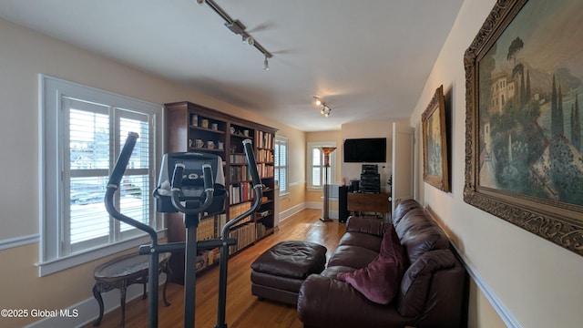 living room featuring wood finished floors, rail lighting, and baseboards