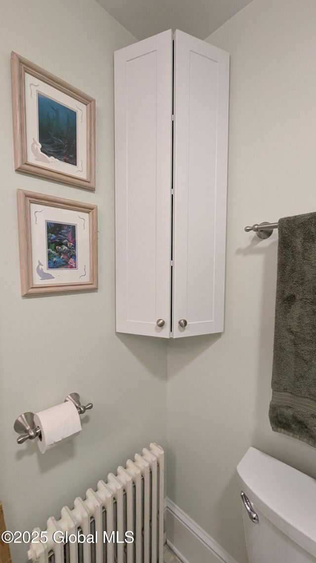 bathroom with radiator, baseboards, and toilet