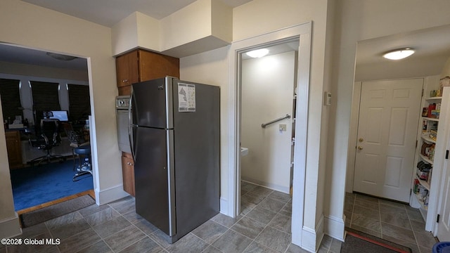 kitchen with brown cabinetry, freestanding refrigerator, oven, and baseboards