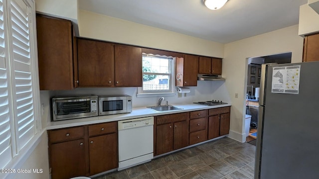 kitchen featuring light countertops, appliances with stainless steel finishes, a sink, and under cabinet range hood