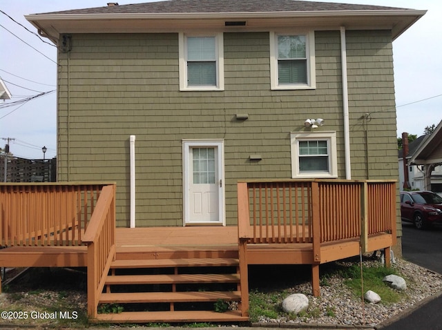 rear view of property with a deck and roof with shingles