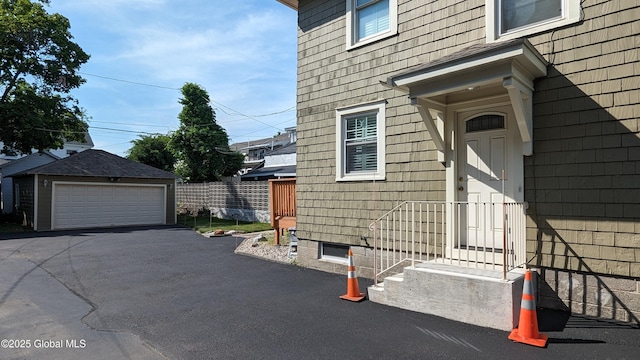 view of side of property featuring entry steps, a detached garage, an outbuilding, and fence