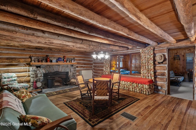 dining room with a wood stove, rustic walls, a notable chandelier, beam ceiling, and wood ceiling