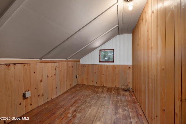 bonus room featuring wood-type flooring, vaulted ceiling, and wood walls