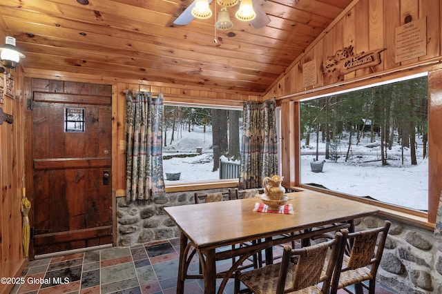 dining space featuring vaulted ceiling, ceiling fan, wooden walls, and wood ceiling