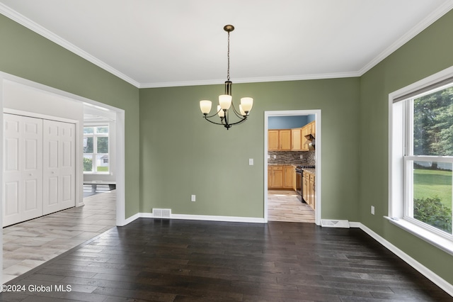 unfurnished dining area with crown molding, dark hardwood / wood-style flooring, a healthy amount of sunlight, and a notable chandelier