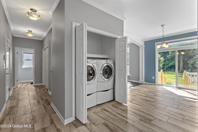 laundry room featuring washing machine and clothes dryer, plenty of natural light, an inviting chandelier, and ornamental molding