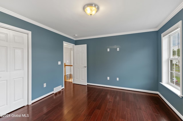 unfurnished bedroom featuring multiple windows, dark hardwood / wood-style flooring, and ornamental molding