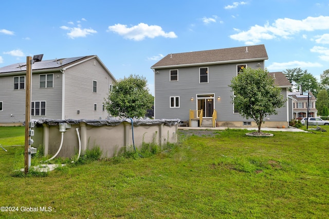 rear view of property featuring a lawn and a covered pool