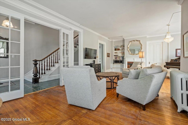 living room with crown molding, radiator heating unit, and built in shelves