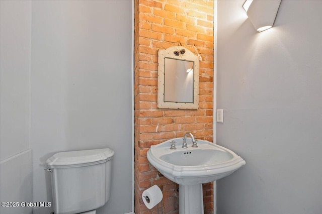 bathroom with brick wall and toilet