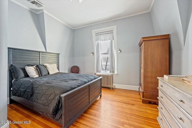 bedroom featuring ornamental molding, radiator, and light hardwood / wood-style flooring