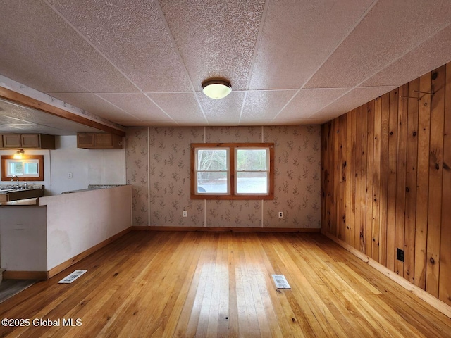 spare room featuring sink, wooden walls, and light hardwood / wood-style flooring