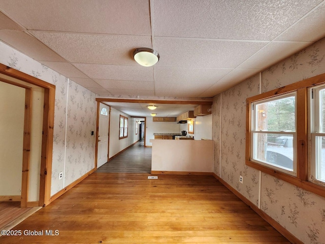 corridor with a paneled ceiling, light hardwood / wood-style flooring, and a healthy amount of sunlight