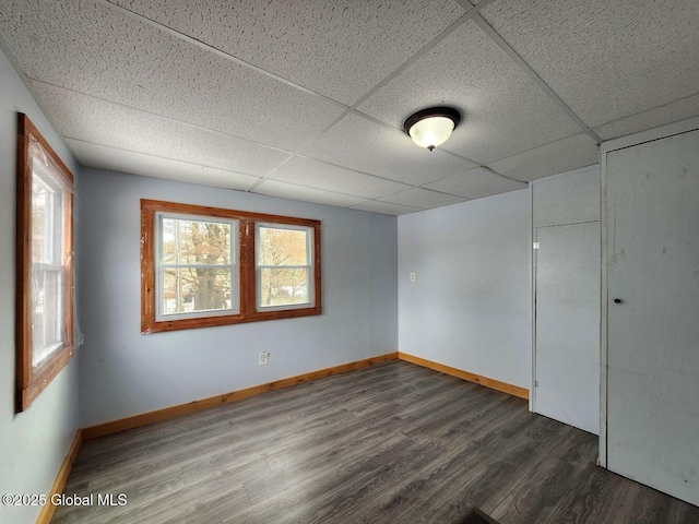 spare room with dark hardwood / wood-style flooring and a paneled ceiling