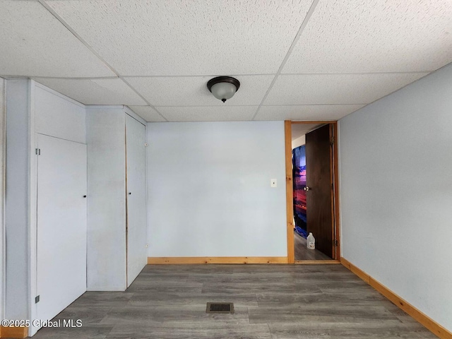 interior space featuring a drop ceiling and dark hardwood / wood-style flooring