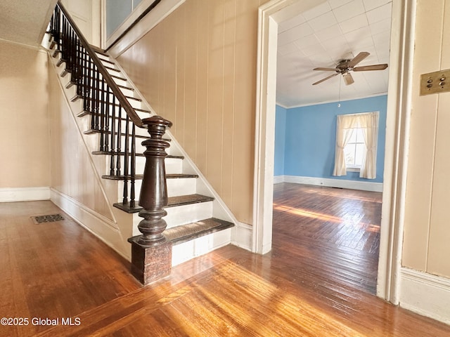 stairs with hardwood / wood-style flooring, ceiling fan, and crown molding