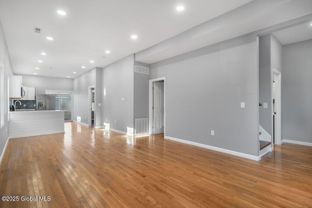 unfurnished living room with light hardwood / wood-style flooring and sink