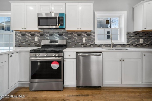 kitchen with white cabinets, decorative backsplash, sink, and appliances with stainless steel finishes