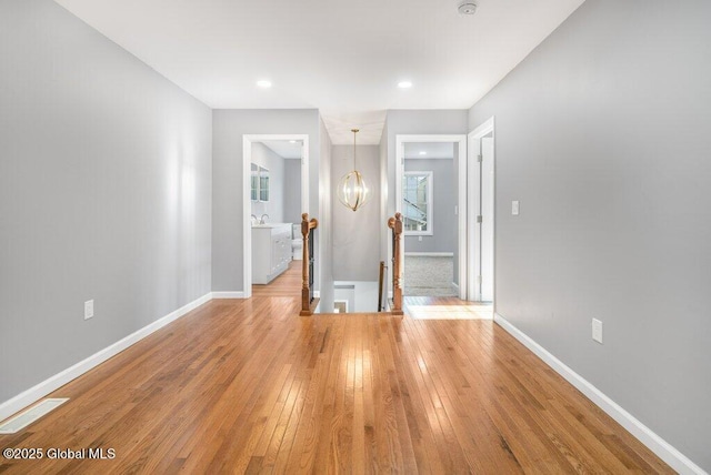 empty room featuring a notable chandelier, wood-type flooring, and sink