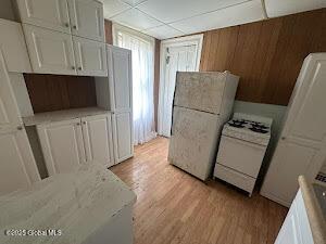 kitchen with white cabinets, white appliances, and light wood-type flooring