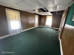 spare room featuring a paneled ceiling and wood walls