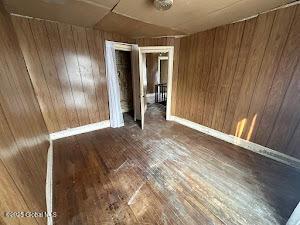 spare room featuring dark hardwood / wood-style flooring and wooden walls