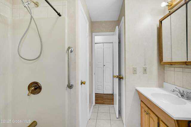 bathroom with tasteful backsplash, tile patterned floors, vanity, and a shower