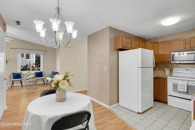 kitchen with backsplash, pendant lighting, white refrigerator, an inviting chandelier, and range