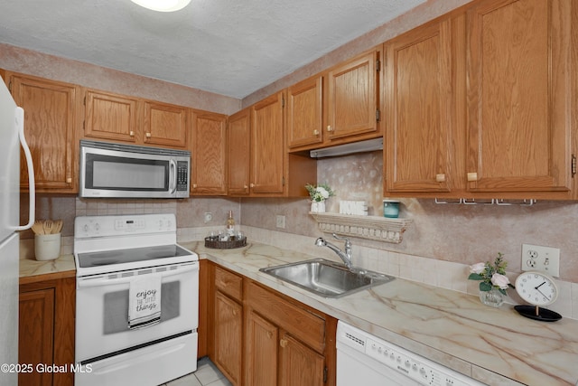 kitchen featuring sink, backsplash, a textured ceiling, white appliances, and light tile patterned floors