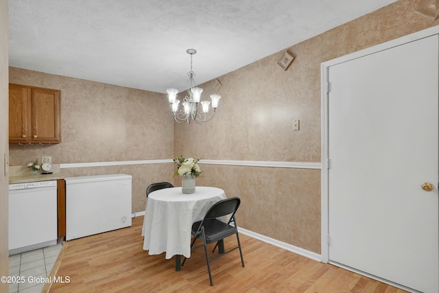 dining area with a notable chandelier, light wood-type flooring, and a textured ceiling