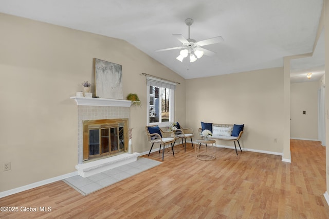 sitting room featuring ceiling fan, vaulted ceiling, a fireplace, and light hardwood / wood-style flooring