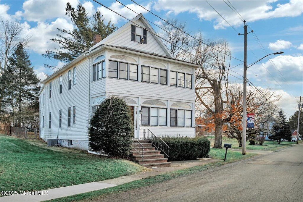 view of front of house with central air condition unit and a front yard