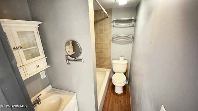 bathroom with toilet, wood-type flooring, tiled shower, and vanity