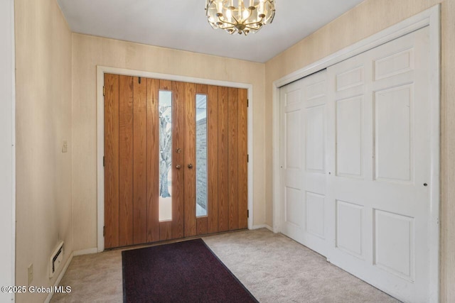 carpeted foyer entrance with a notable chandelier