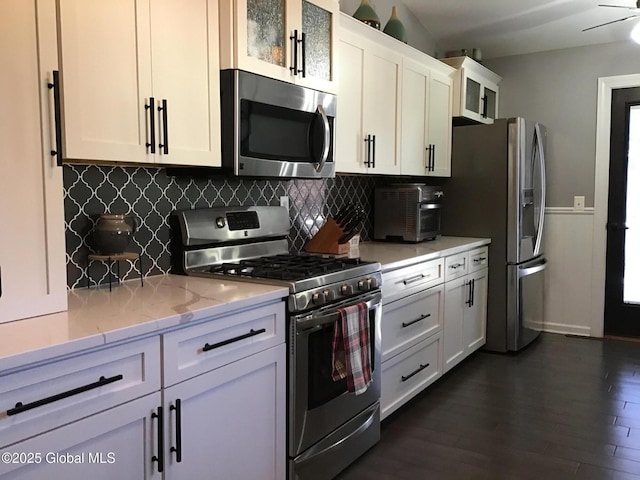 kitchen featuring white cabinets, decorative backsplash, light stone countertops, dark hardwood / wood-style flooring, and stainless steel appliances