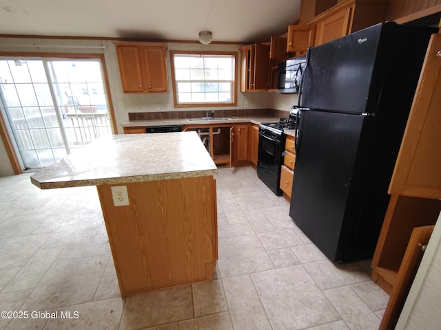 kitchen featuring sink, a center island, a healthy amount of sunlight, and black appliances