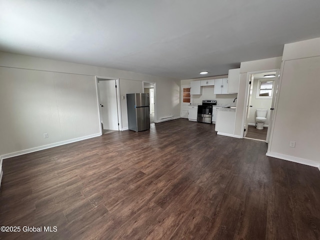 unfurnished living room featuring a sink, baseboards, baseboard heating, and dark wood-style flooring