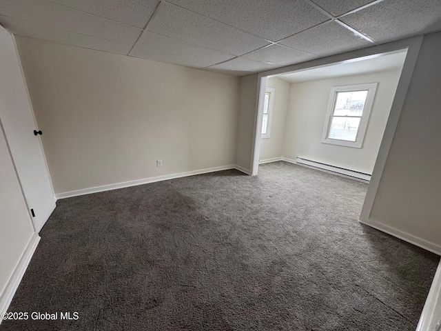 spare room with baseboards, a drop ceiling, dark carpet, and baseboard heating