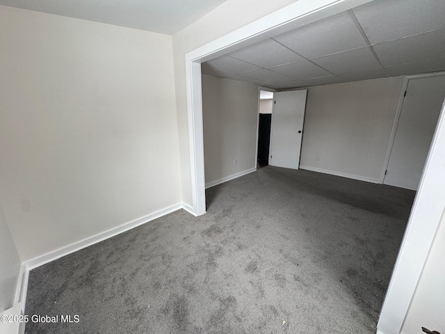 spare room featuring carpet flooring, a paneled ceiling, and baseboards