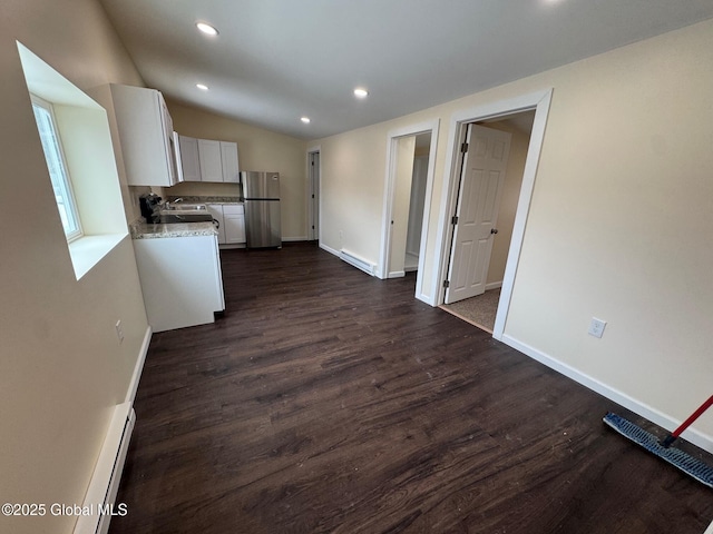 kitchen featuring white cabinets, lofted ceiling, dark wood-style flooring, freestanding refrigerator, and light stone countertops