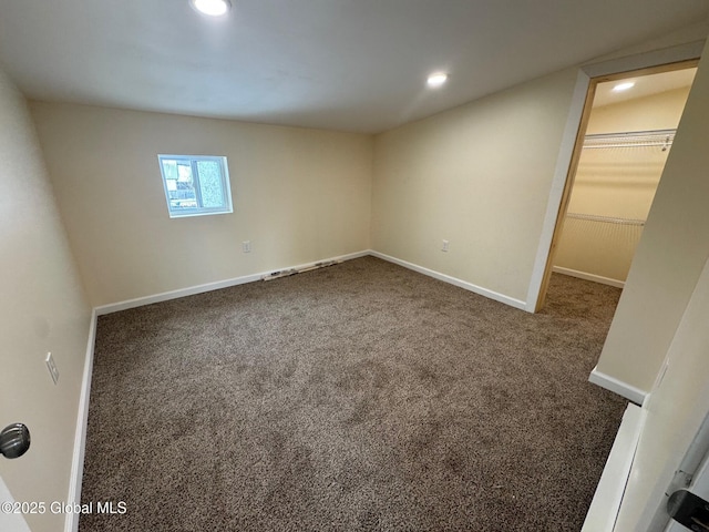 unfurnished bedroom featuring recessed lighting, carpet flooring, a walk in closet, and baseboards