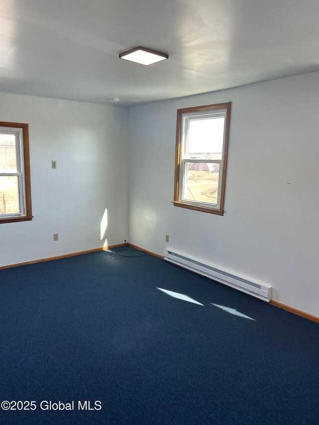 unfurnished room featuring a baseboard heating unit, plenty of natural light, carpet, and baseboards