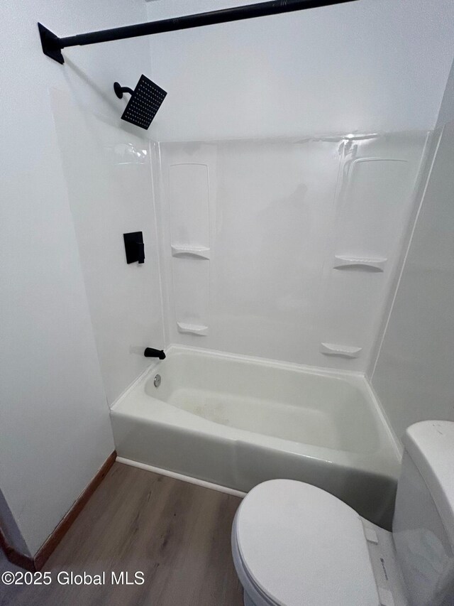 bathroom with baseboards, toilet, shower / washtub combination, and wood finished floors