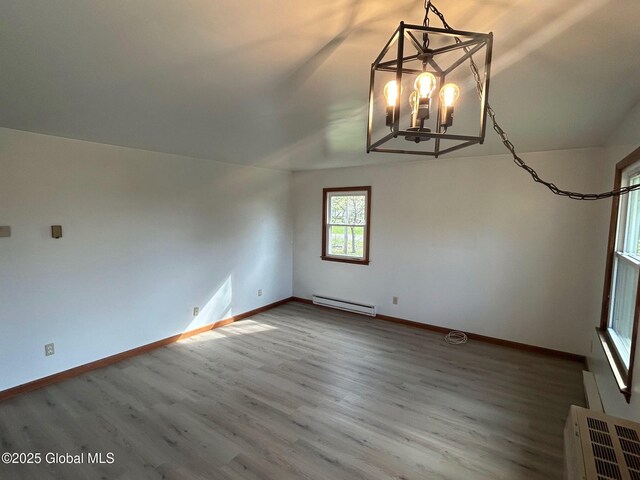 unfurnished room featuring a baseboard radiator, baseboards, an inviting chandelier, and wood finished floors