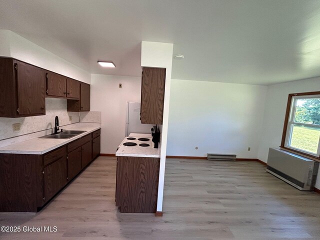 kitchen with light countertops, radiator heating unit, dark brown cabinets, and a sink