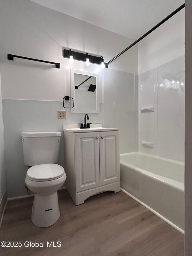 bathroom featuring shower / bathtub combination, toilet, vanity, and wood finished floors