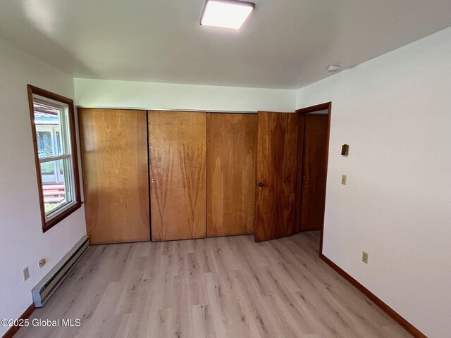 unfurnished bedroom featuring baseboards, light wood-style floors, a closet, and a baseboard radiator